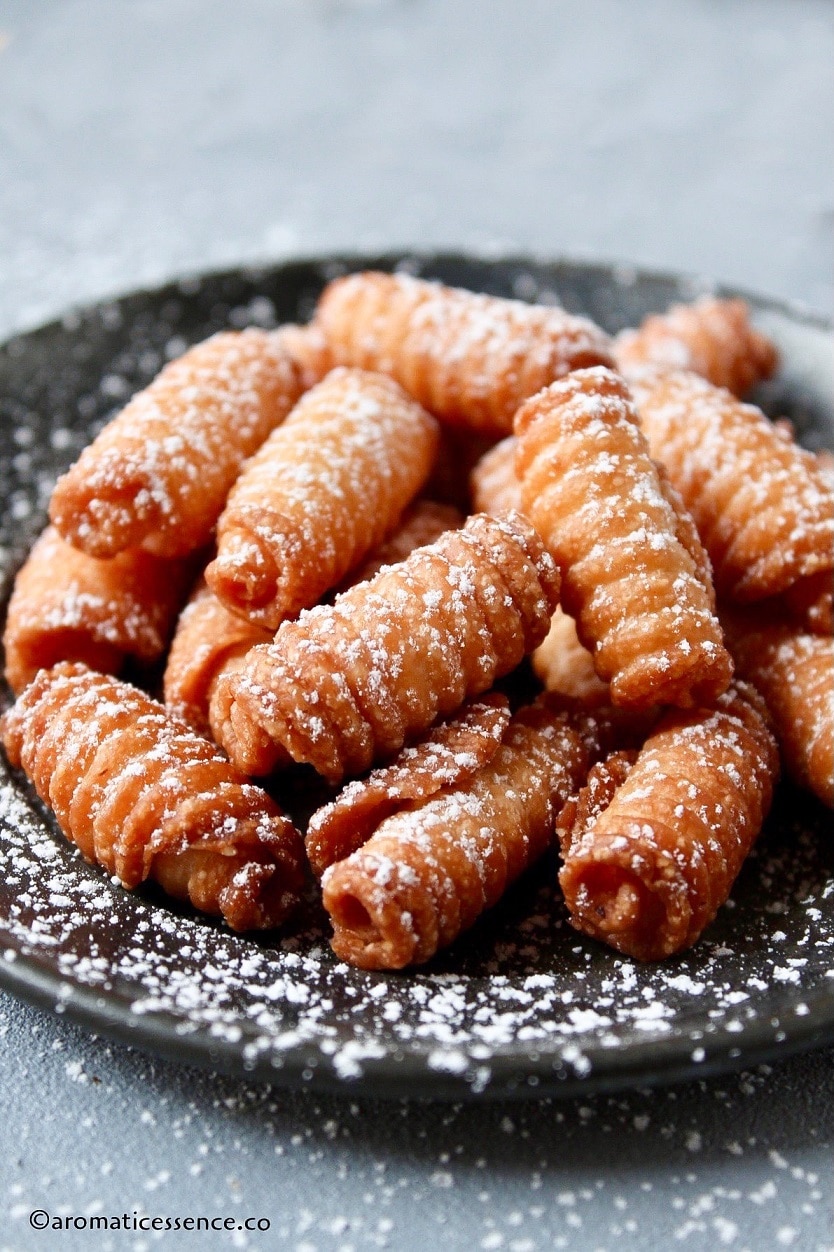 Kalkal dusted with powdered sugar served in a black metal plate