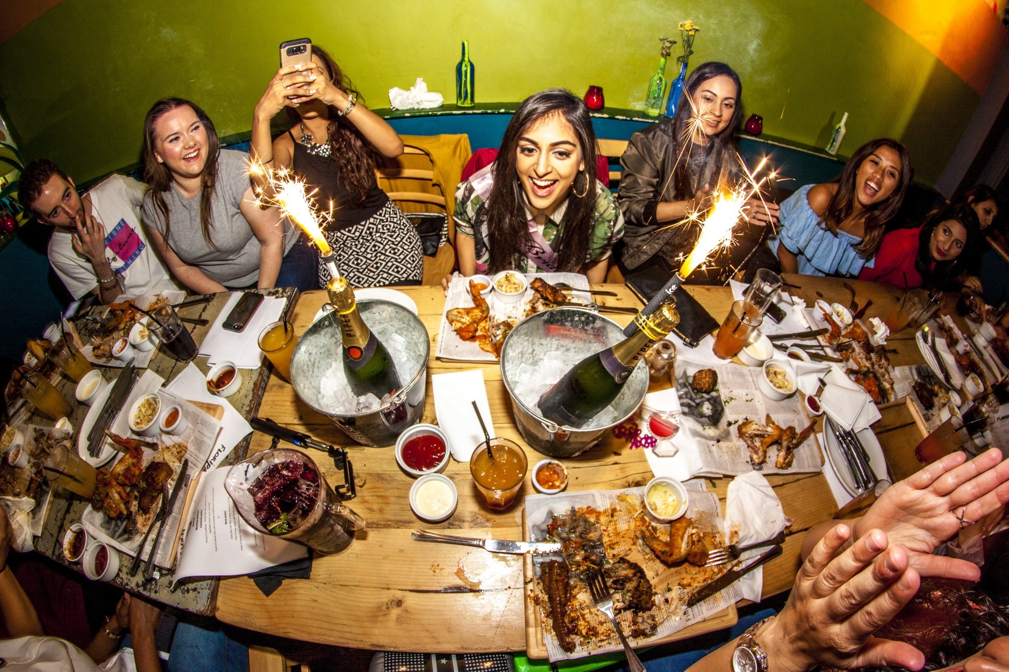 locals gathered around a table with champagne and plates of food