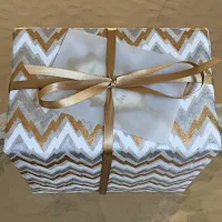 wedding gift wrapped in silver, gold, and white zigzag design paper with gold ribbon and translucent vellum envelope containing leaf gift card