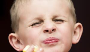 Young boy eating a lemon.