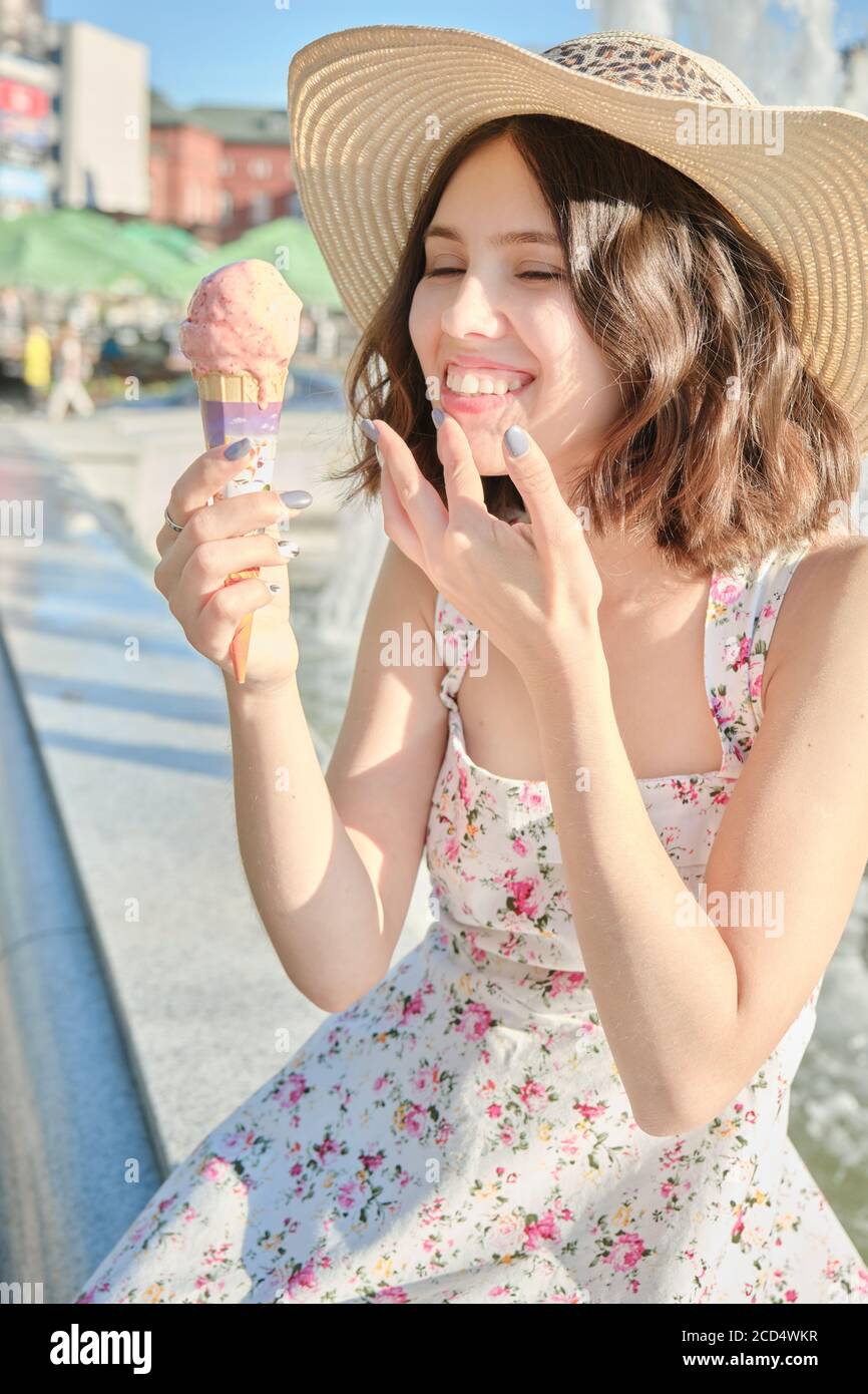 happy young woman in sunhat eats ice-cream, smiling Stock Photo