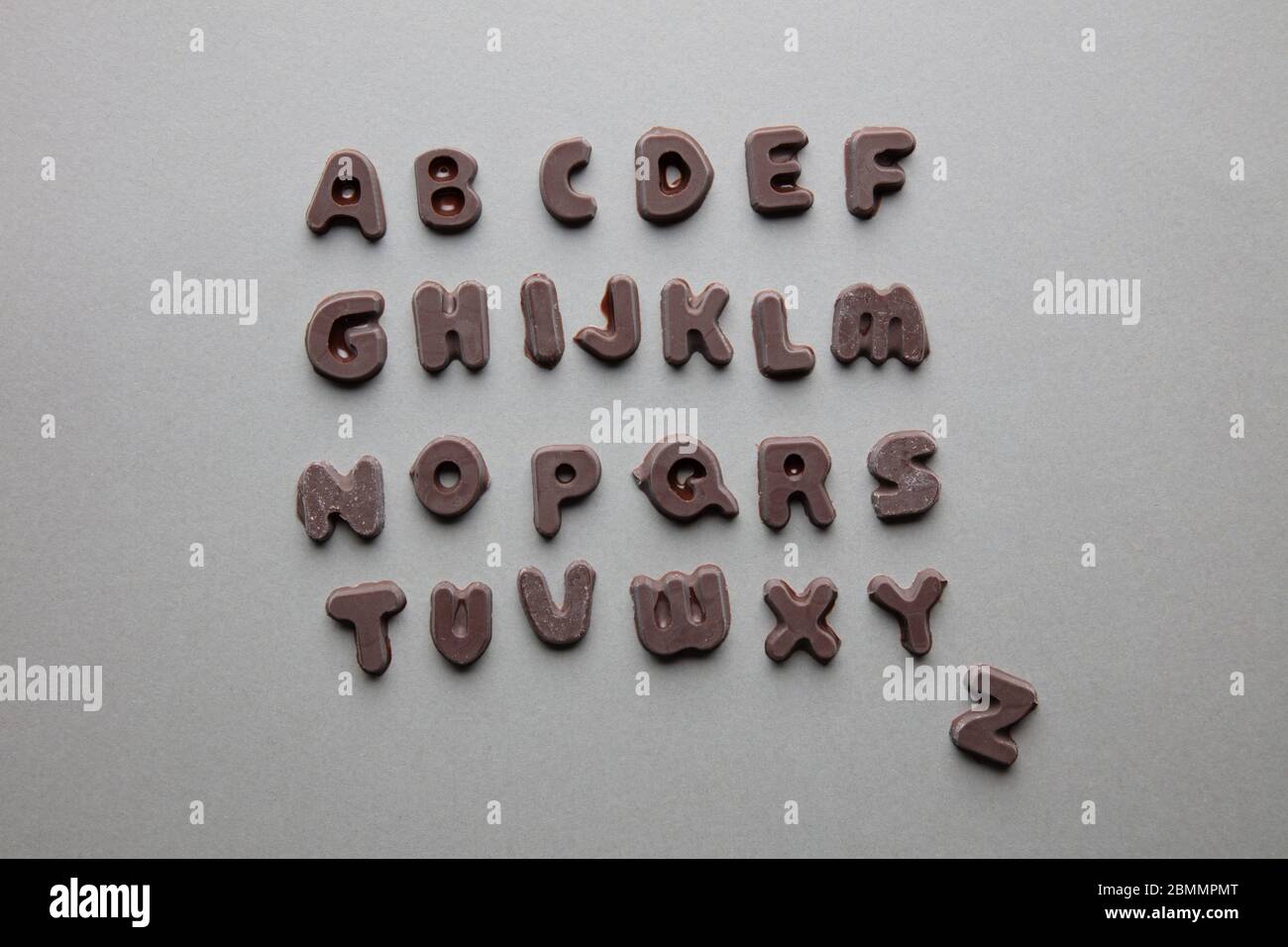 an artsy studio shot of chocolate letters in alphabetical order against a grey background Stock Photo