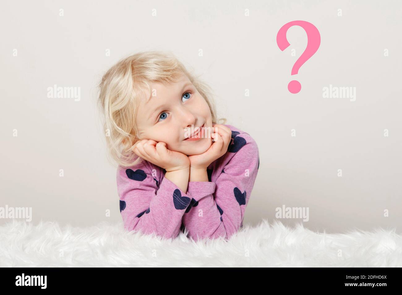 Cute adorable pensive Caucasian girl thinking and dreaming about something. Pink question mark on light simple background. Concept of trouble, problem Stock Photo