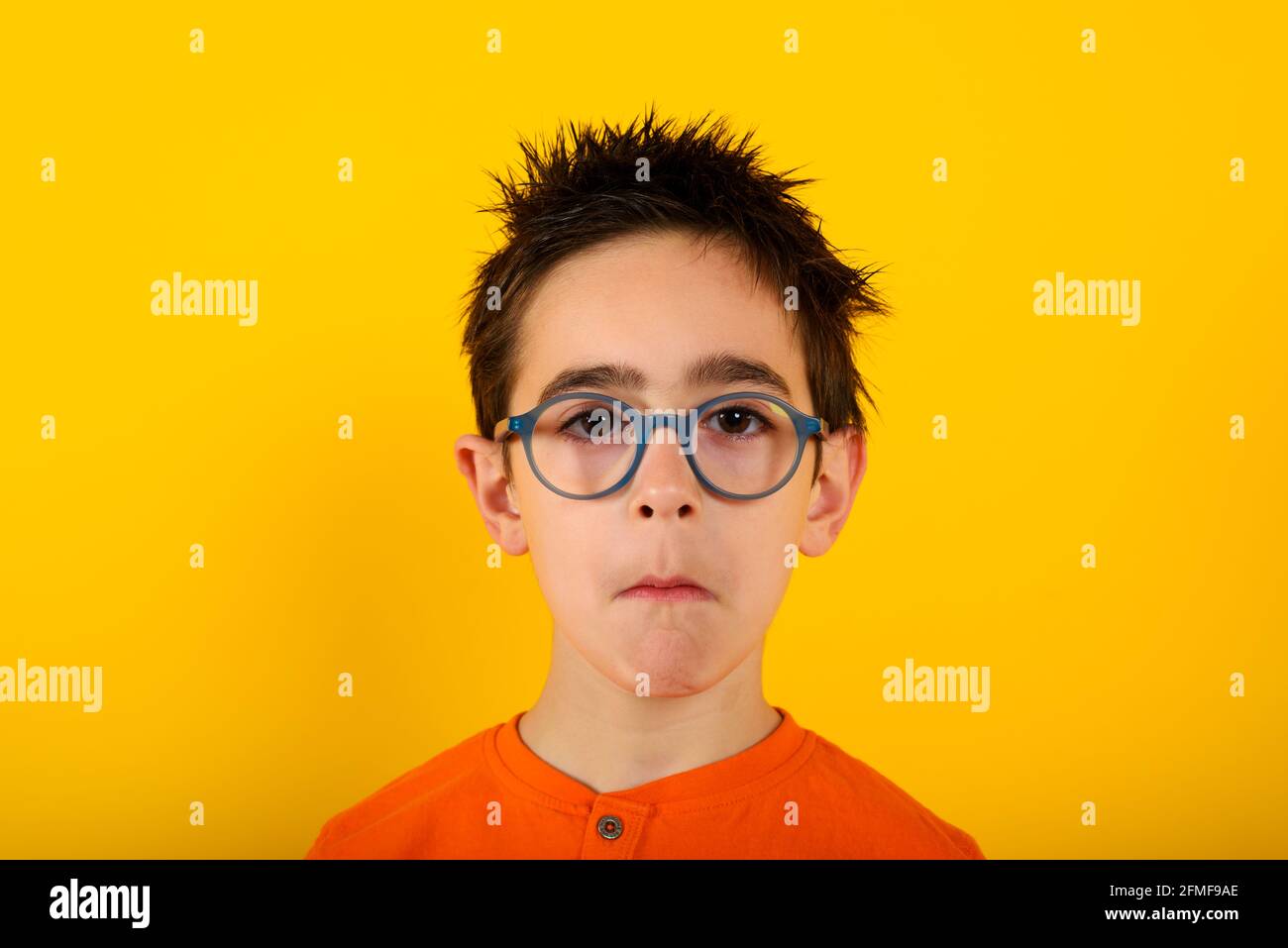 Child is not sure about something and has some questions. yellow background Stock Photo