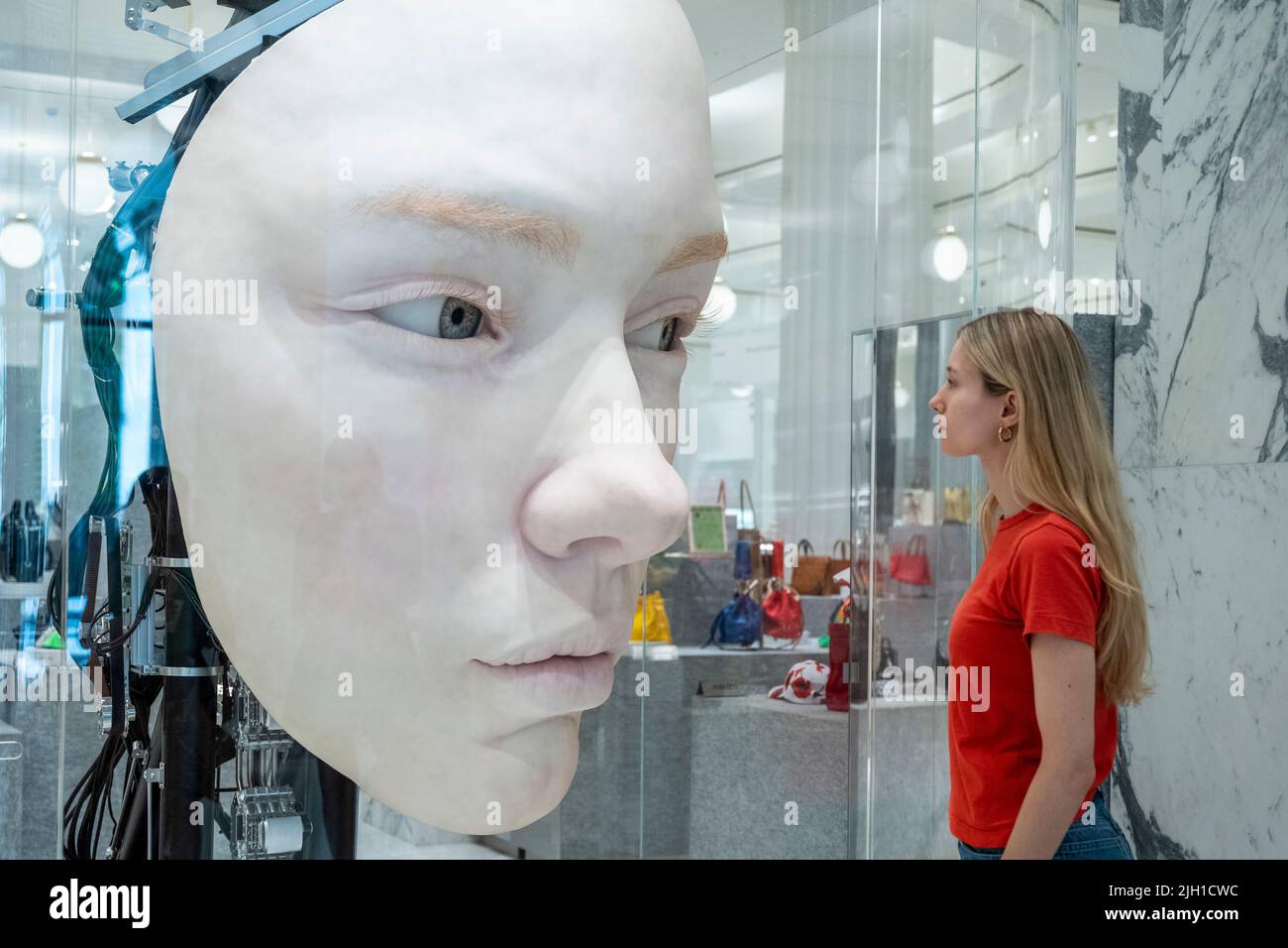 London, UK.  14 July 2022. A staff member views 'The Giant', 2021, by Gentle Monster, a nine foot tall face with hyper realistic movements and expressions at a preview of SUPERFUTURES, a new exhibition at Selfridges, Oxford Street.  13 major large-scale immersive art works on display across the store and windows present contemporary artists’ visions for the futures.  The exhibition is part of Selfridges’ initiative called ‘reinventing retail’ and runs to 15 October 2022. Credit: Stephen Chung / Alamy Live News Stock Photo