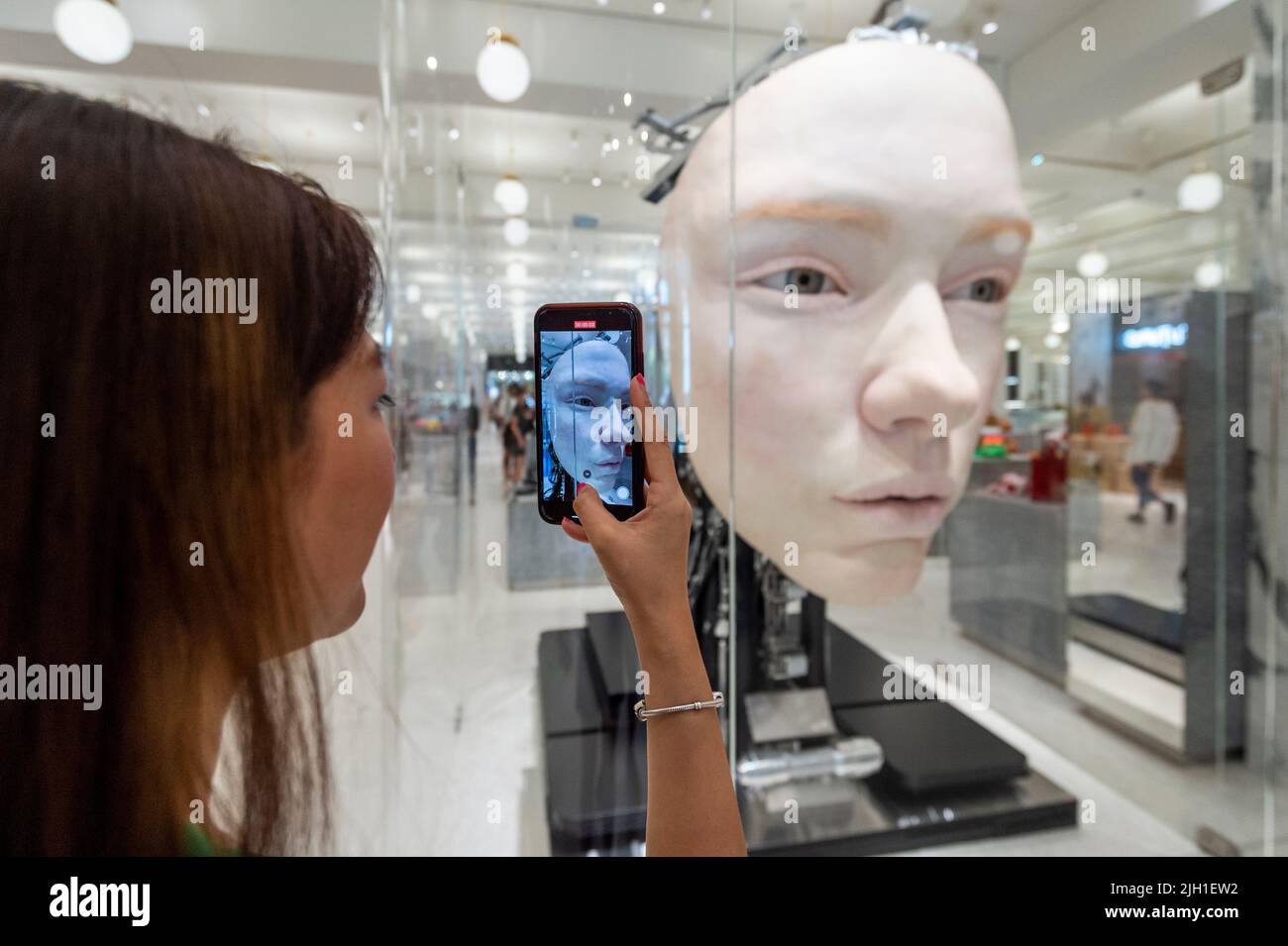 London, UK.  14 July 2022. A staff member views 'The Giant', 2021, by Gentle Monster, a nine foot tall face with hyper realistic movements and expressions at a preview of SUPERFUTURES, a new exhibition at Selfridges, Oxford Street.  13 major large-scale immersive art works on display across the store and windows present contemporary artists’ visions for the futures.  The exhibition is part of Selfridges’ initiative called ‘reinventing retail’ and runs to 15 October 2022. Credit: Stephen Chung / Alamy Live News Stock Photo