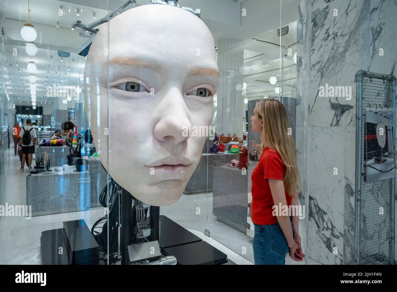 London, UK.  14 July 2022. A staff member views 'The Giant', 2021, by Gentle Monster, a nine foot tall face with hyper realistic movements and expressions at a preview of SUPERFUTURES, a new exhibition at Selfridges, Oxford Street.  13 major large-scale immersive art works on display across the store and windows present contemporary artists’ visions for the futures.  The exhibition is part of Selfridges’ initiative called ‘reinventing retail’ and runs to 15 October 2022. Credit: Stephen Chung / Alamy Live News Stock Photo