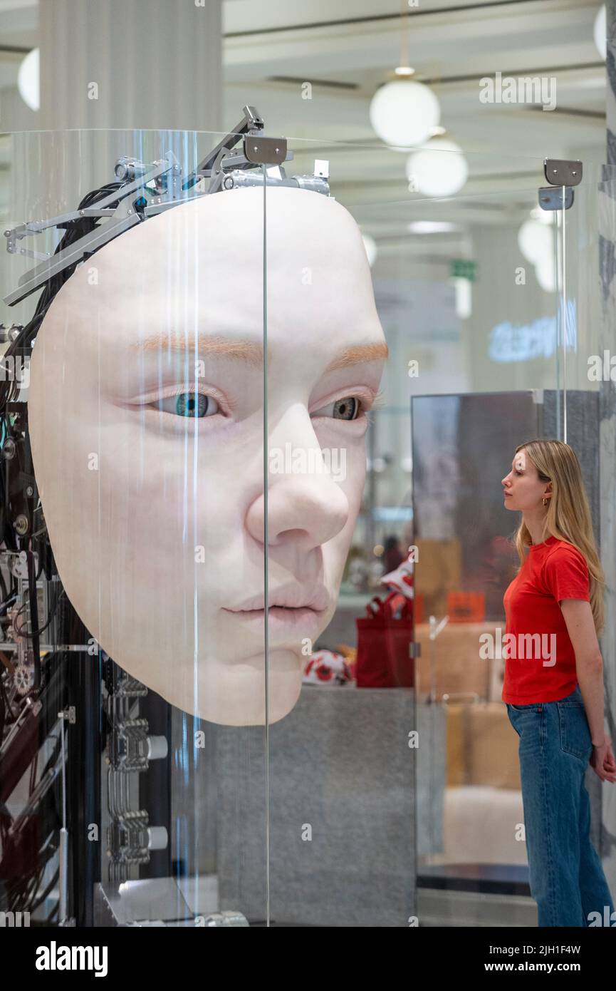 London, UK.  14 July 2022. A staff member views 'The Giant', 2021, by Gentle Monster, a nine foot tall face with hyper realistic movements and expressions at a preview of SUPERFUTURES, a new exhibition at Selfridges, Oxford Street.  13 major large-scale immersive art works on display across the store and windows present contemporary artists’ visions for the futures.  The exhibition is part of Selfridges’ initiative called ‘reinventing retail’ and runs to 15 October 2022. Credit: Stephen Chung / Alamy Live News Stock Photo