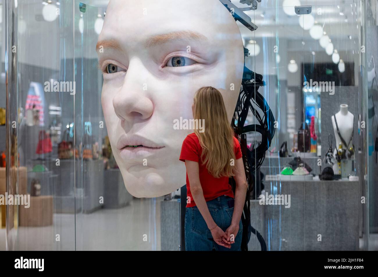 London, UK.  14 July 2022. A staff member views 'The Giant', 2021, by Gentle Monster, a nine foot tall face with hyper realistic movements and expressions at a preview of SUPERFUTURES, a new exhibition at Selfridges, Oxford Street.  13 major large-scale immersive art works on display across the store and windows present contemporary artists’ visions for the futures.  The exhibition is part of Selfridges’ initiative called ‘reinventing retail’ and runs to 15 October 2022. Credit: Stephen Chung / Alamy Live News Stock Photo