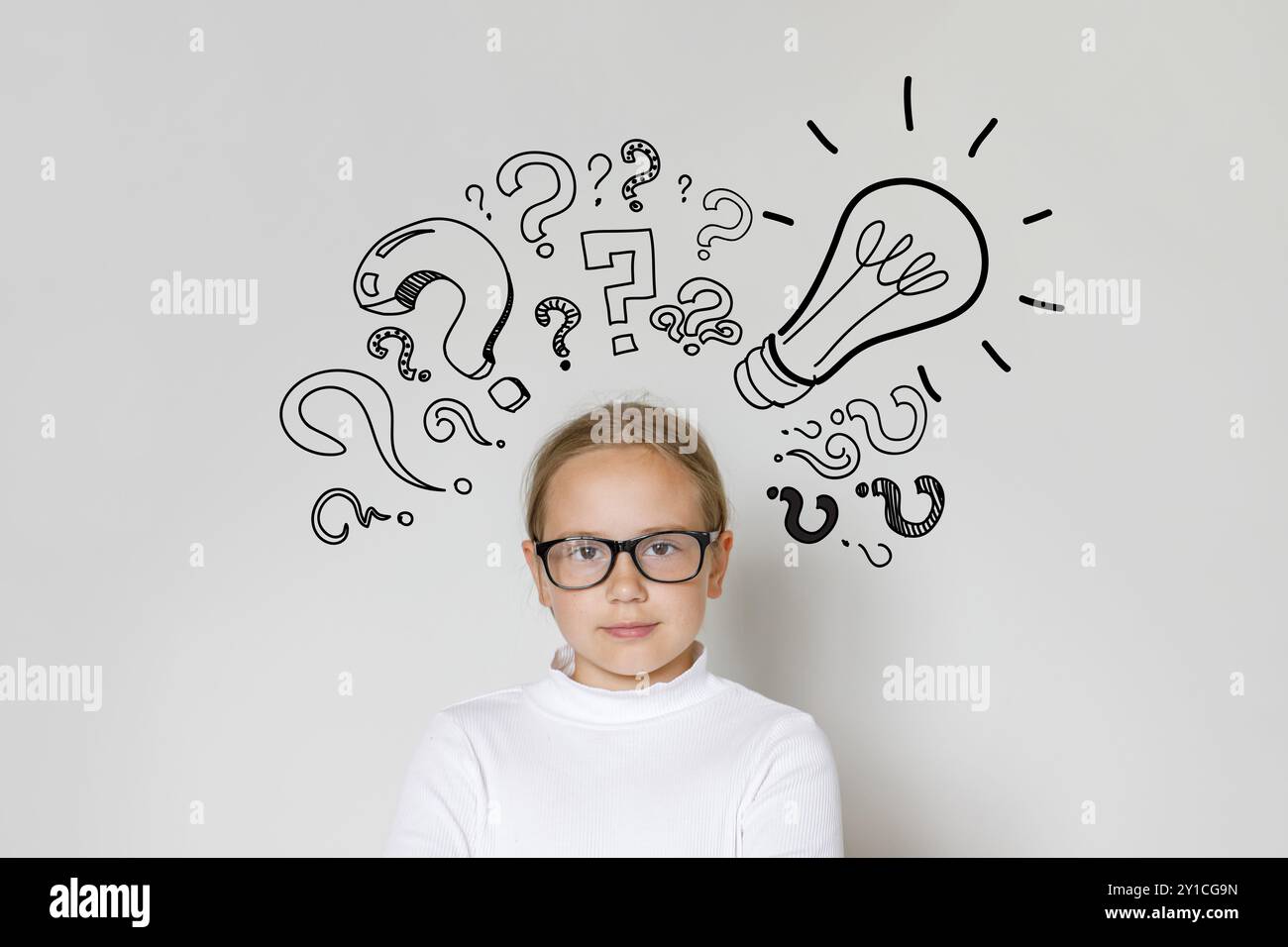 Young child girl in guggles with light bulb and question marks looking at camera on white background. Education and idea concept Stock Photo