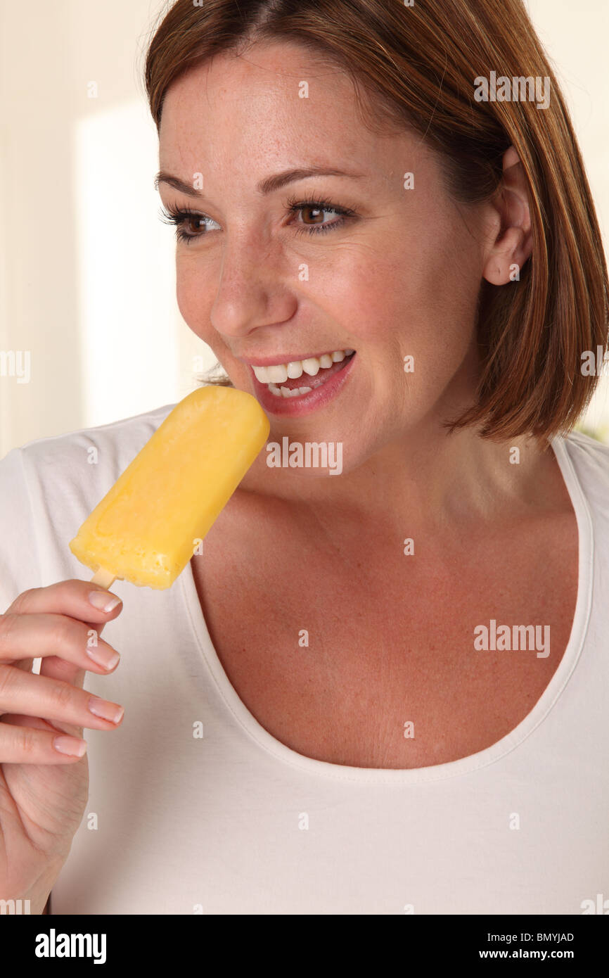 WOMAN EATING ORANGE ICE LOLLY OR POPSICLE Stock Photo