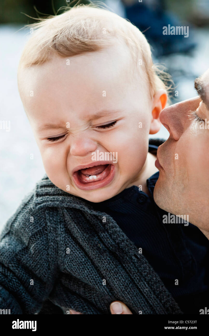 Father kissing crying baby Stock Photo