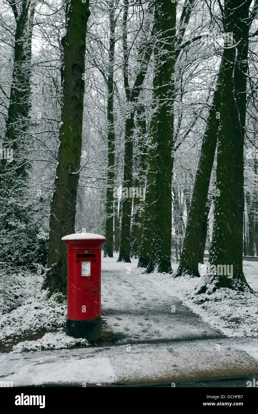 Red Pillar Box, snow and trees Stock Photo