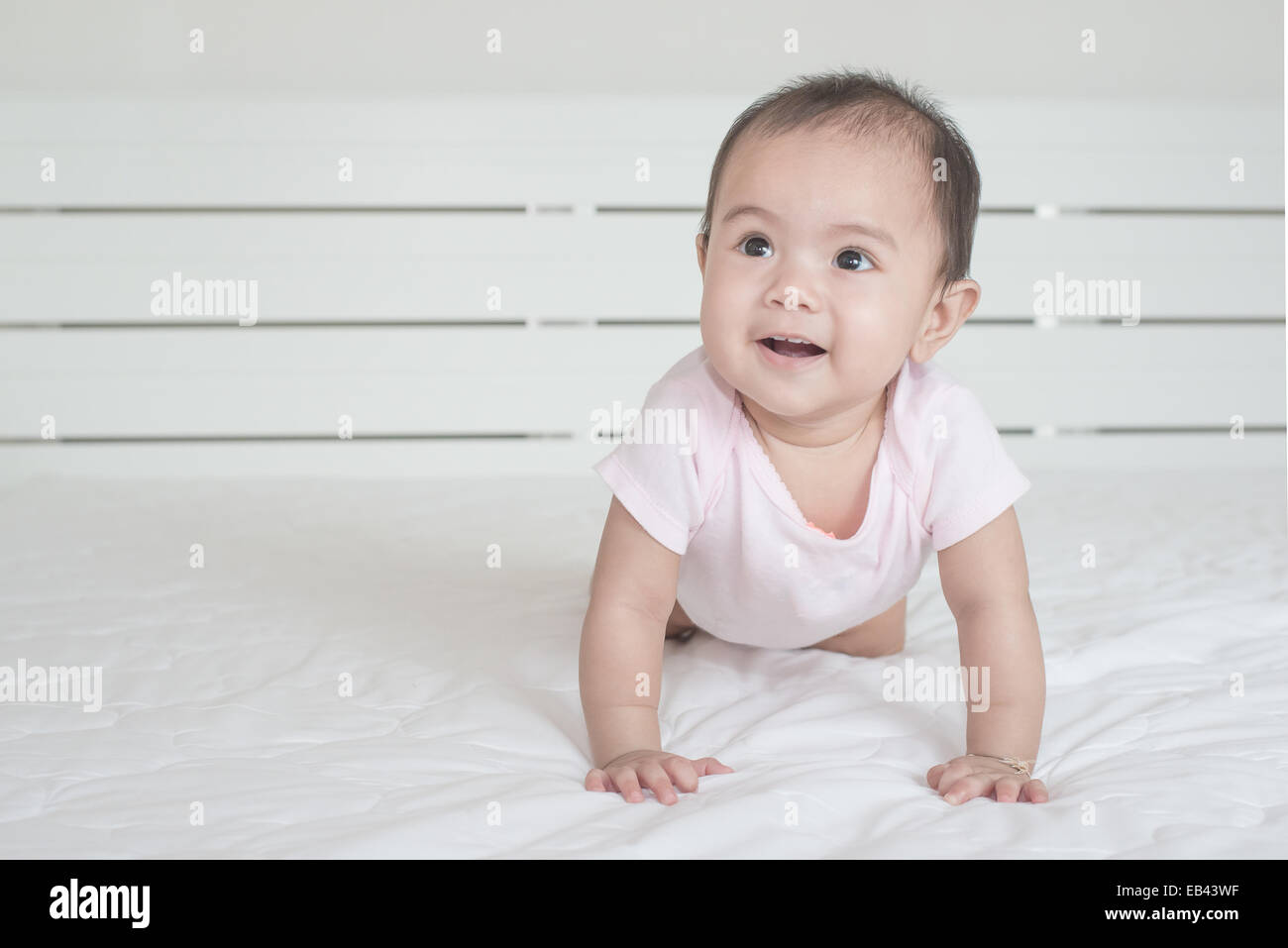 Asian baby crawling in bedroom Stock Photo