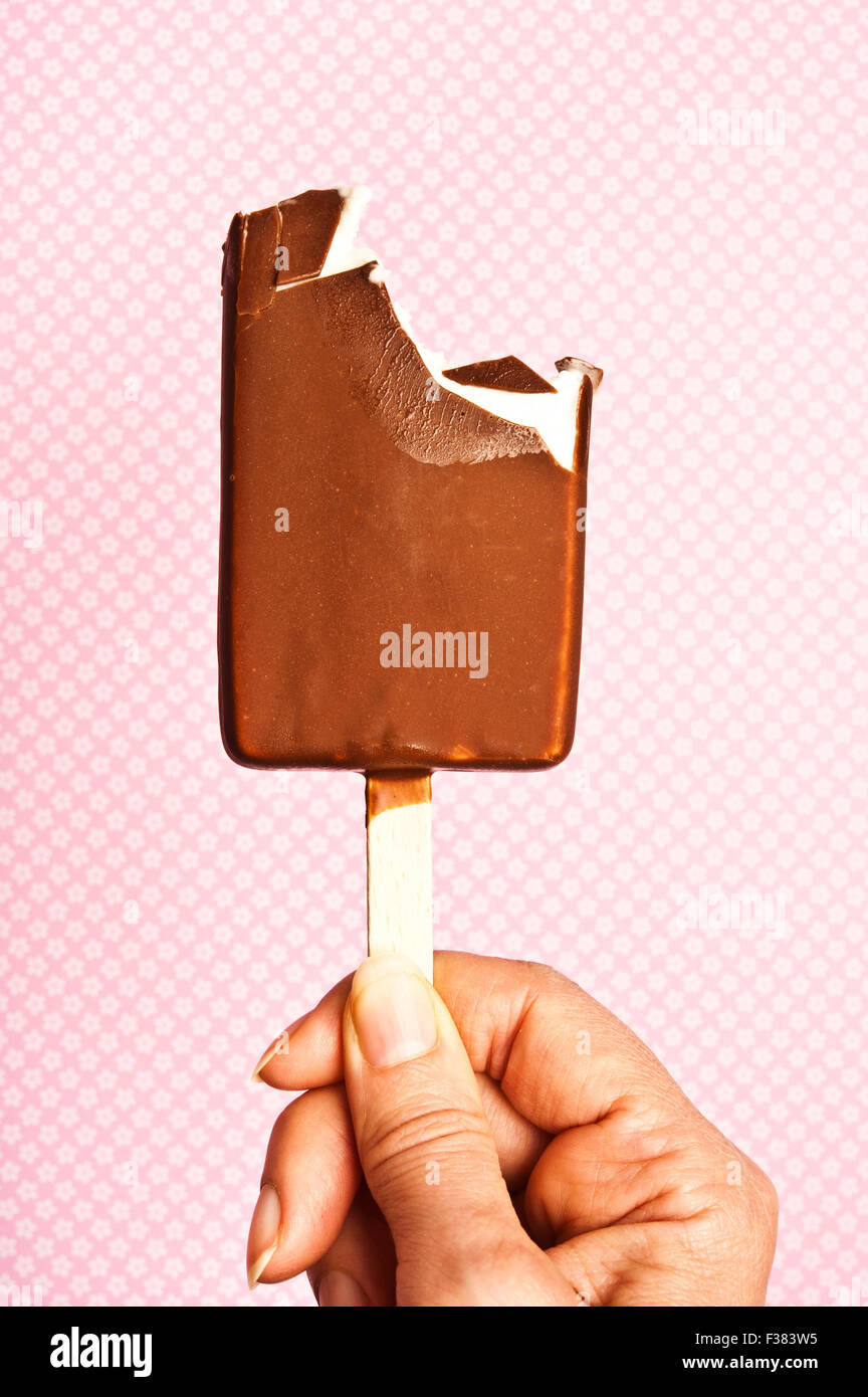 woman hand holding a partially eaten chocolate ice lolly Stock Photo