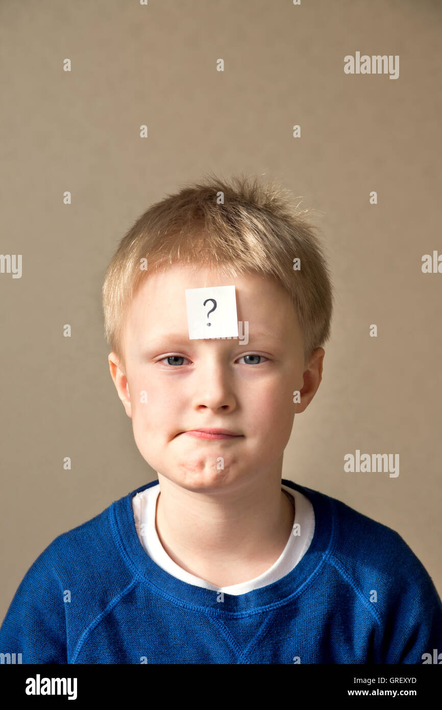 thinking young boy with question mark has secret on gray background Stock Photo