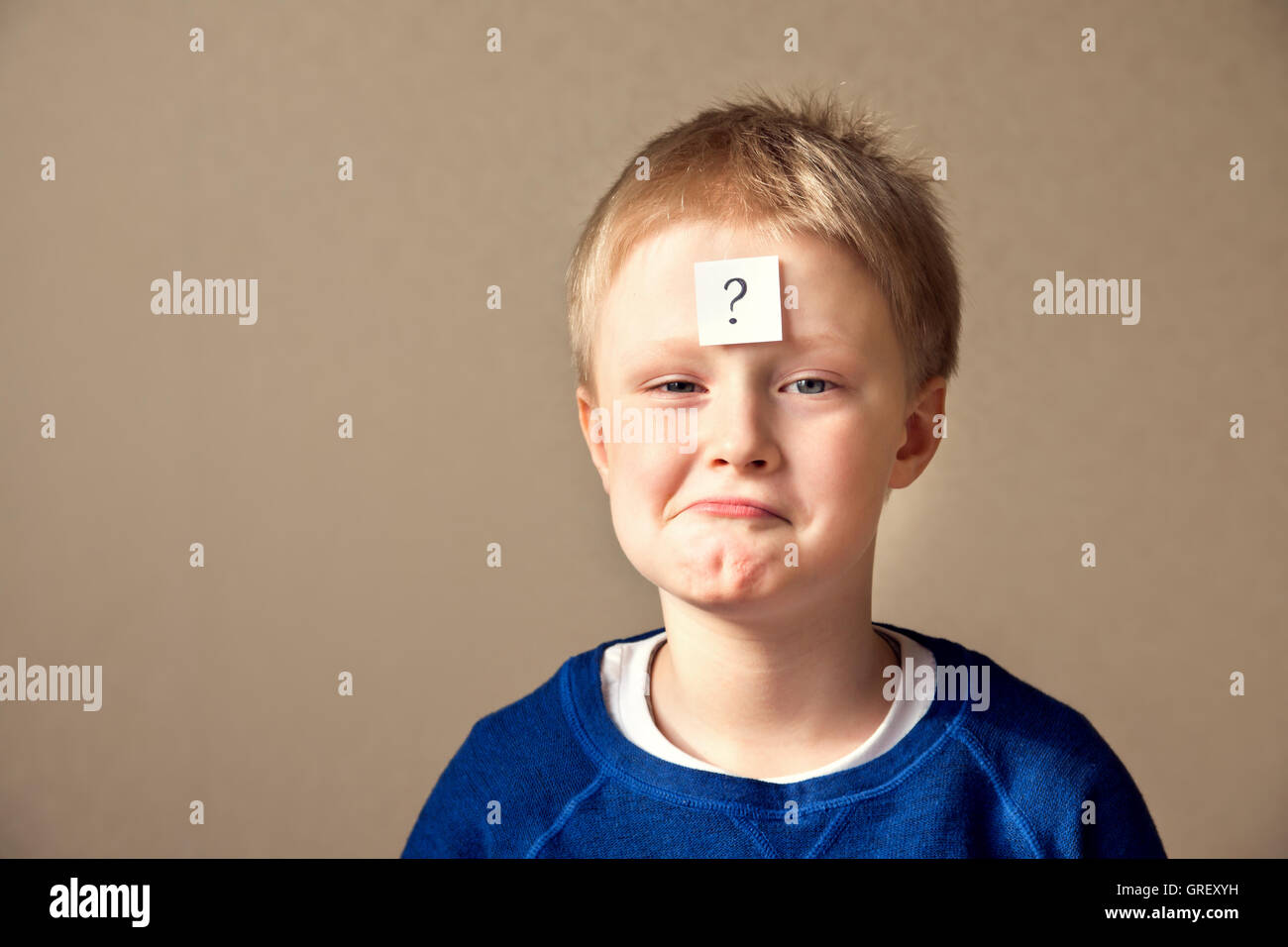 thinking young boy with question mark has secret on gray background Stock Photo