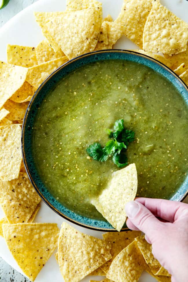 top view of dipping tortilla chip into a bowl of easy salsa verde