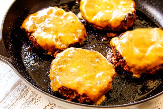 showing how to make burgers on the stove by topping each of the 4 patties with a slice of cheese