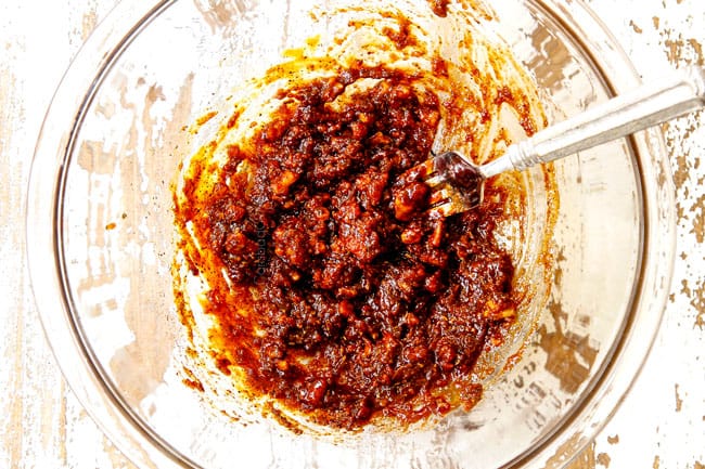 showing how to make burgers by mashing panade into a paste in a glass bowl