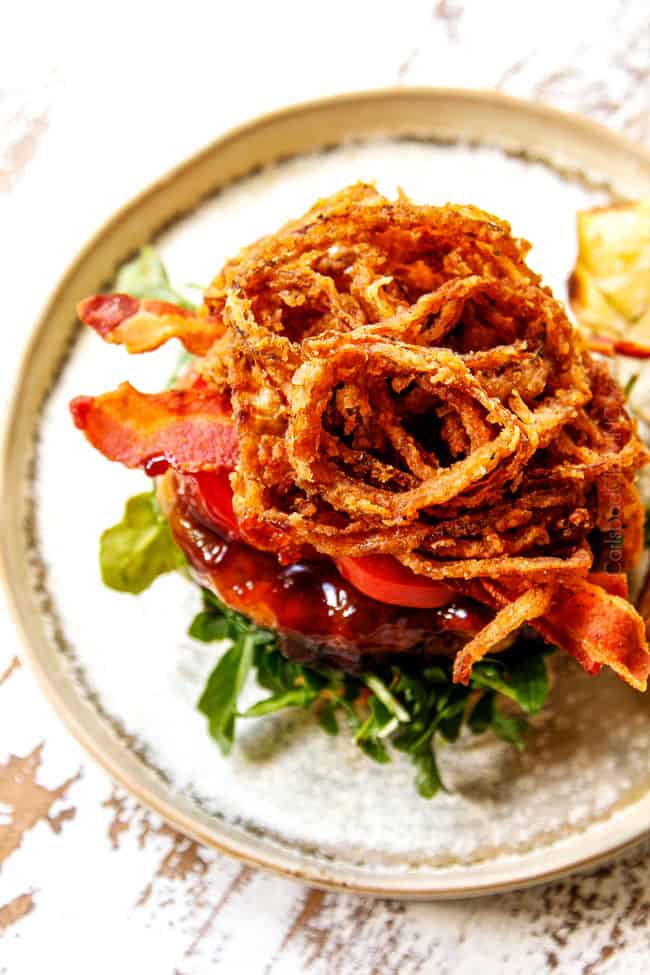 showing how to make BBQ burger recipe by stacking with bacon and fried onion strings