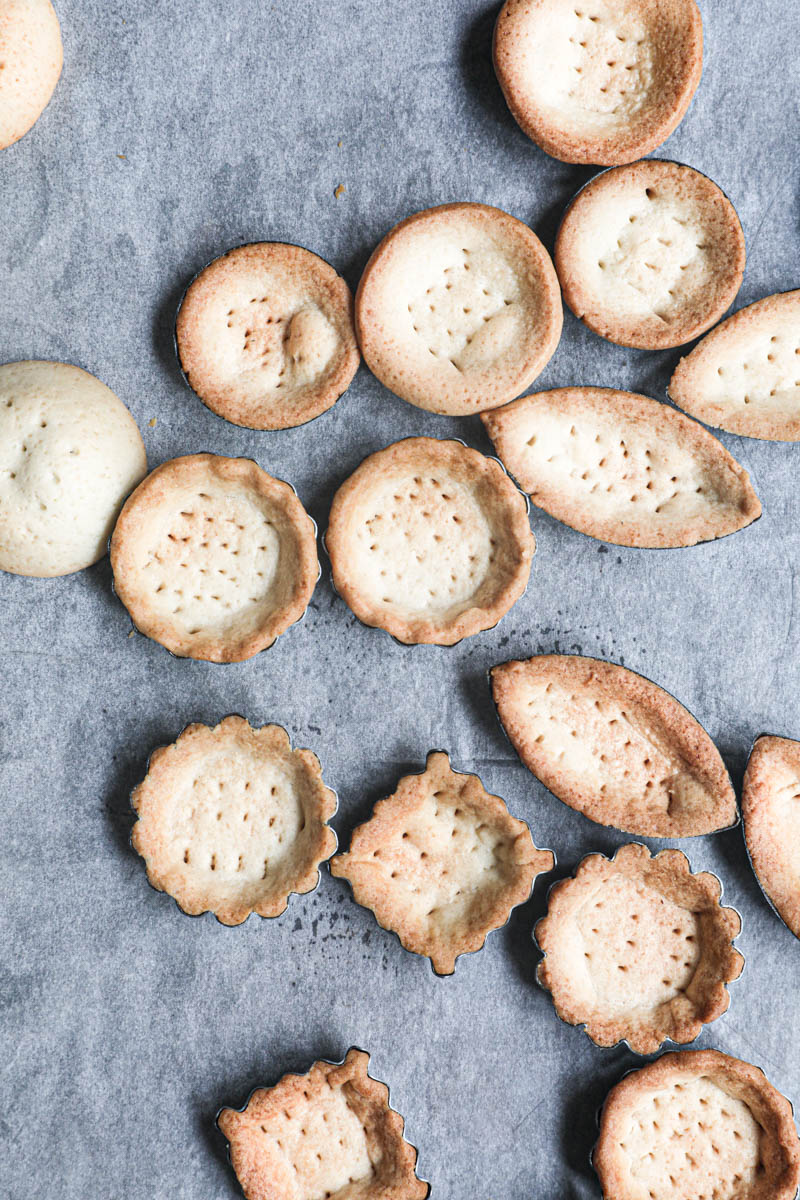 The pre-baked mini tartlet shells on a piece of parchment paper.