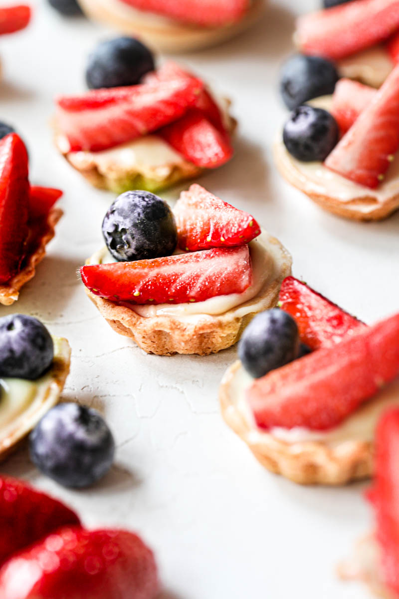 The assembled strawberry lemon mini tartlets as seen from the side with others blurry on the back.