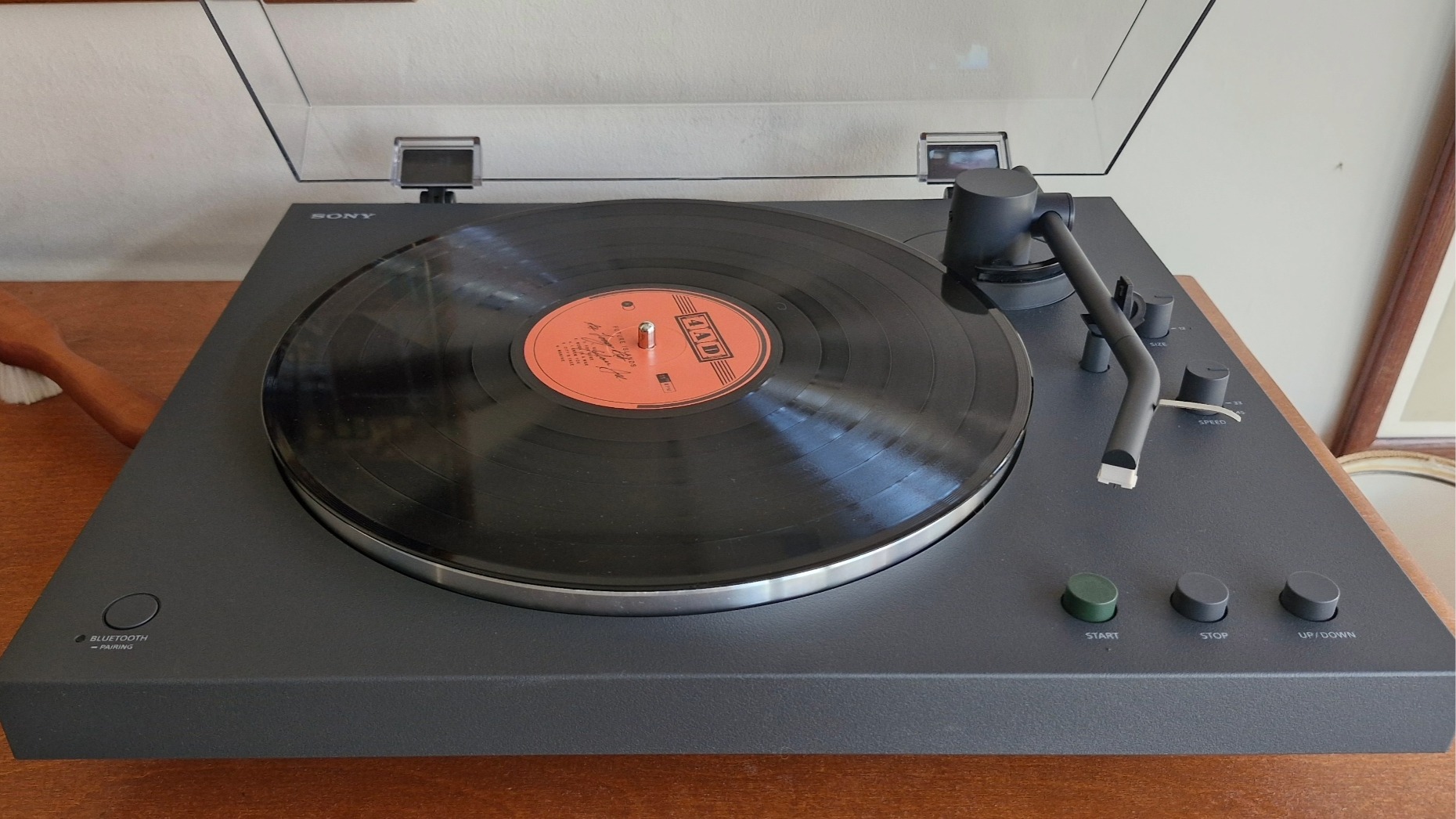 The Sony PS-LX3BT turntable, with the dust cover open, on a wooden surface.