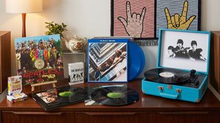 Seveal Beatles vinyl albums on a wooden sideboard, with a Beatles-branded suitcase turntable, plus some Beatles playing cards and A Hard Day's Night on Blu-ray