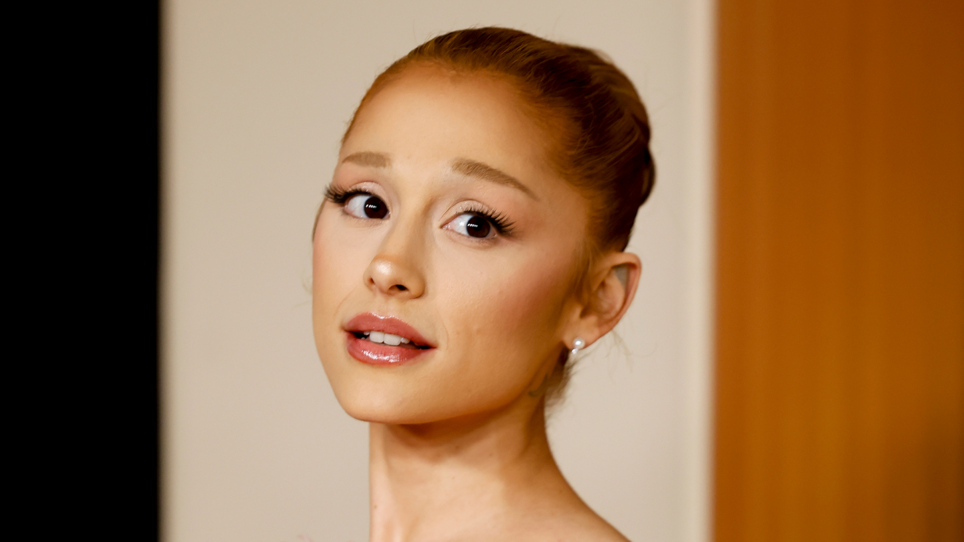 Ariana Grande wearing a bun hairstyle and looking at the camera