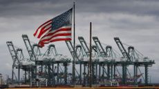 The US flag flies over shipping cranes and containers 