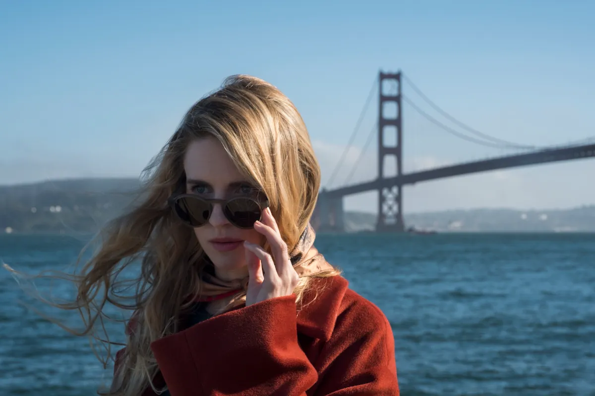 brit marling as prairie wearing a red coat and sunglasses by the golden gate bridge in the oa