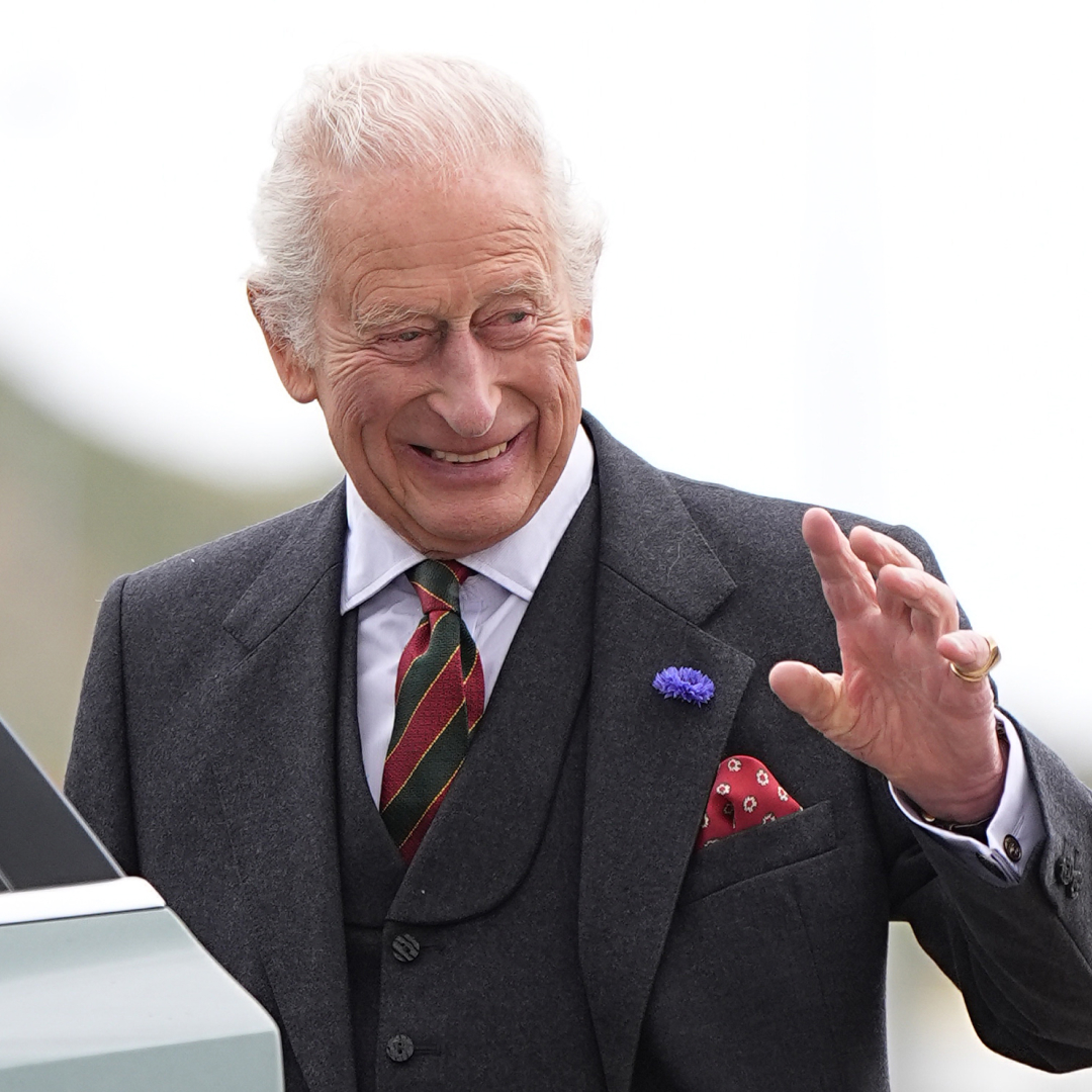 King Charles waving and smiling while getting into a car