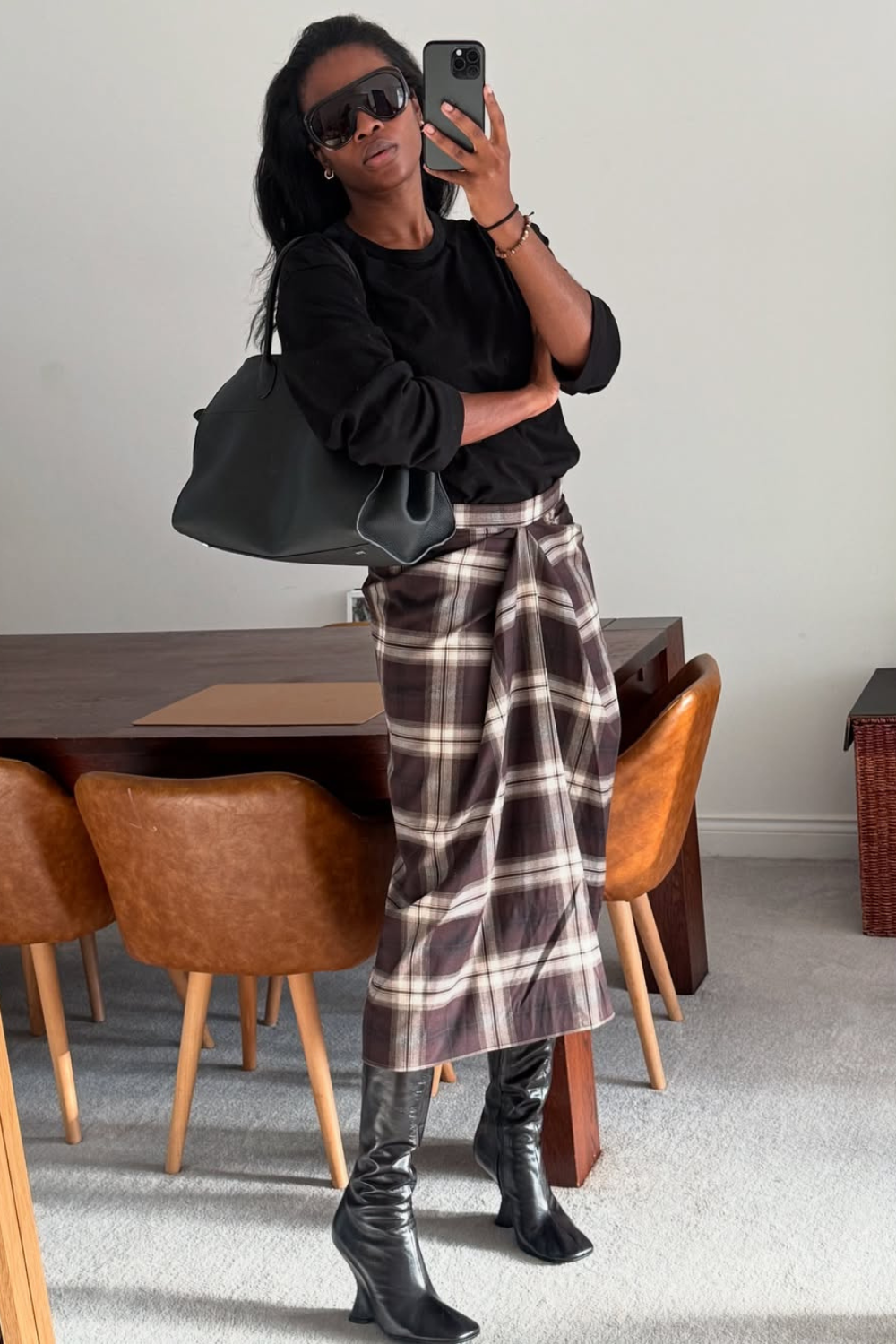 @nlmarilyn wears checked skirt, black jumper knee-high boots