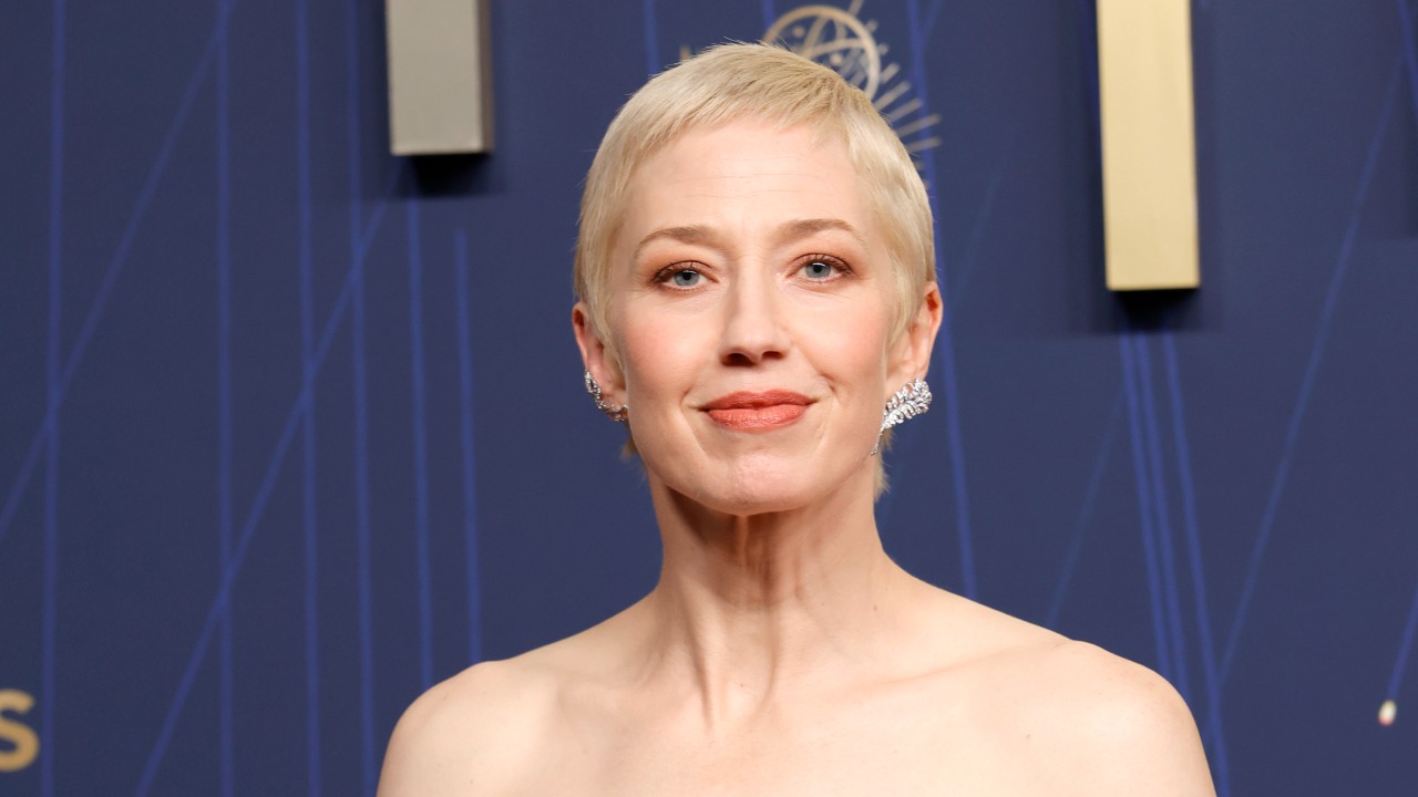 a woman with short, blonde hair wearing a baby blue gown taking a photo in front of a blue background