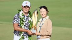 Si Woo Kim of South Korea poses with his wife Ji Hyun Oh and the trophy after putting in to win on the 18th green during the final round of the Sony Open in Hawaii at Waialae Country Club on January 15, 2023 in Honolulu, Hawaii.