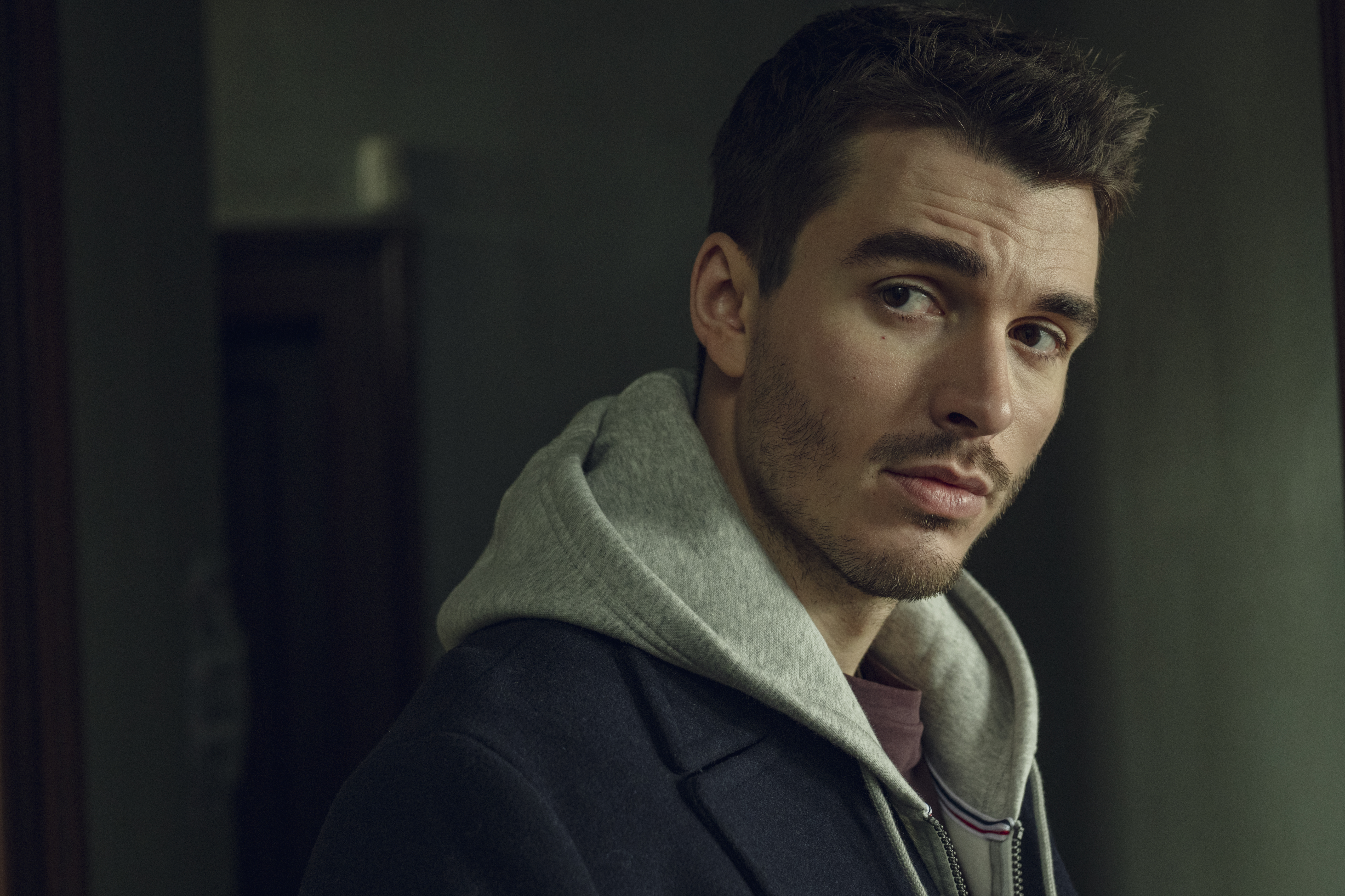 Corey Mylchreest as Matheo wearing a sweatshirt and looking mysterious in hostage