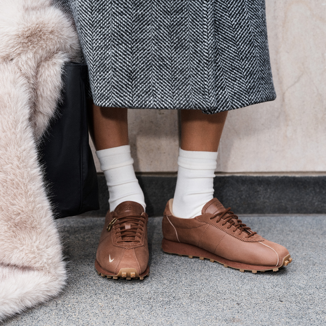 a model wearing the Nike x Aritzia sneaker collaboration on the street with a coat