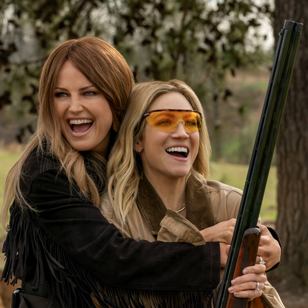 Malin Akerman as Margo hugging brittany snow as sophie from behind and showing her how to shoot a riffle in the tv show hunting wives