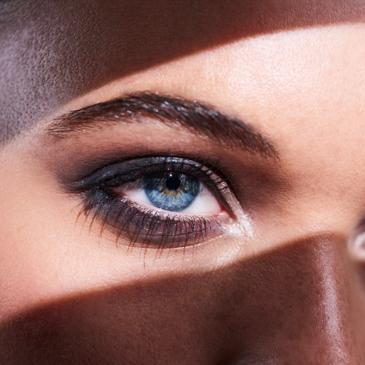 close-up of a woman&#039;s blue eyes with a shadow running across her face