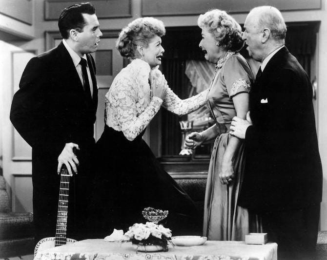 a black and white still from the sitcom I Love Lucy of two women looking concerned and their husbands looking shocked
