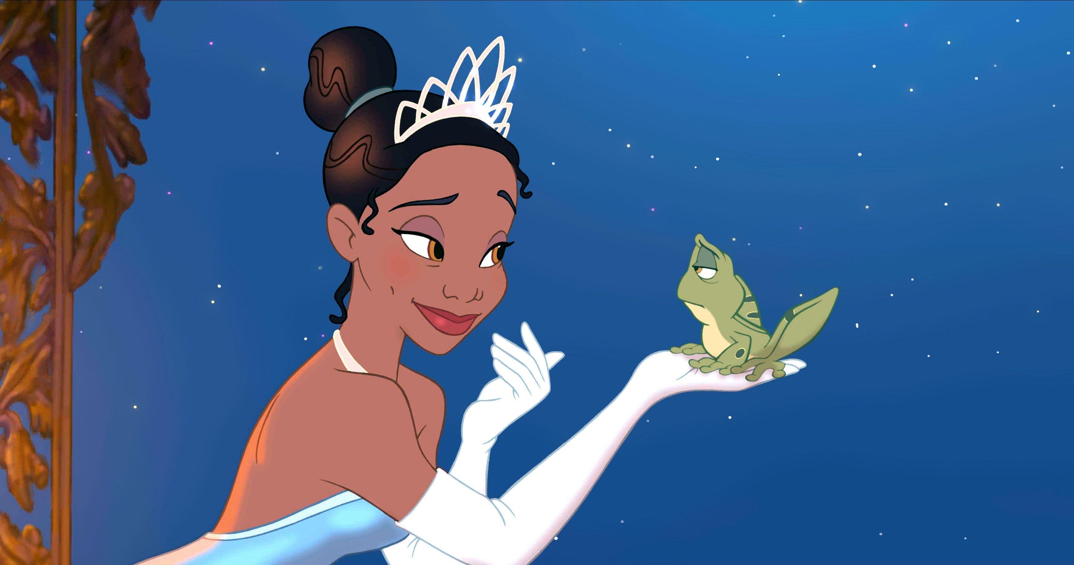 princess tiana in a tiara and blue dress leaning in to kiss a green frog she's holding in The Princess and the Frog