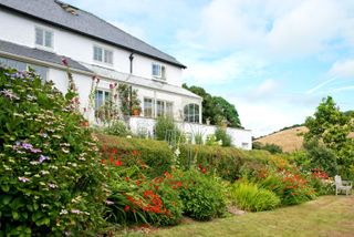 tiered garden ideas: shrubs along slope down to lawn