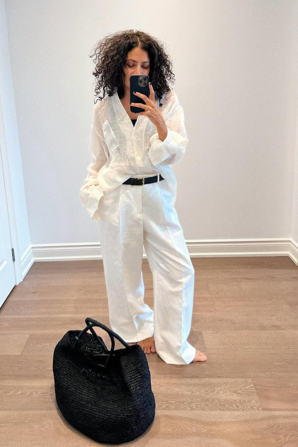 @neelam.ahooja wears white linen trousers, shirt and black belt with black bag