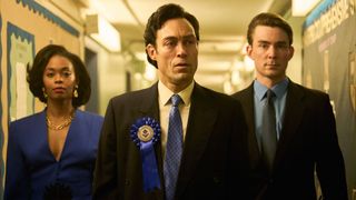 Cameron, Rupert and an assistant walk down a hallway
