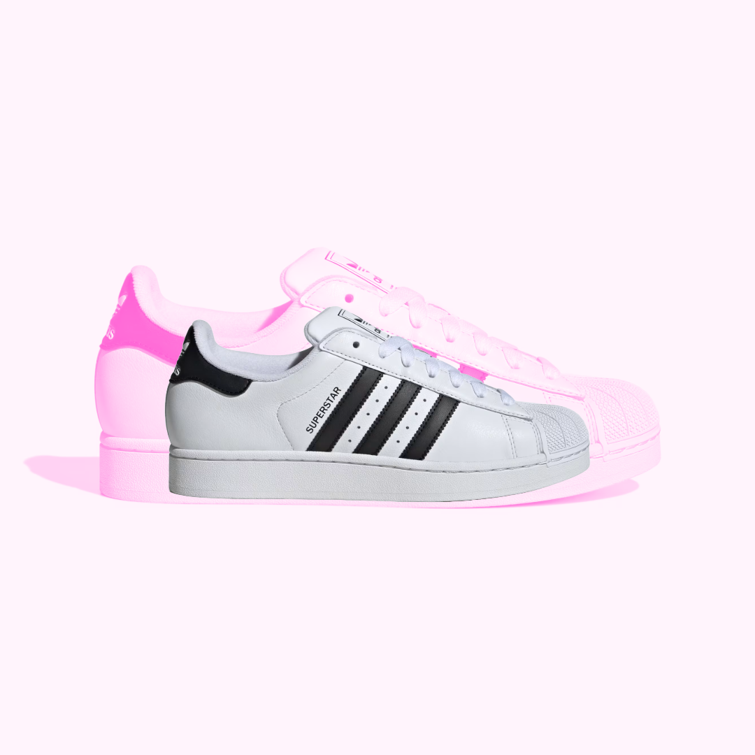 Adidas Superstar Sneakers in white on a pink background.