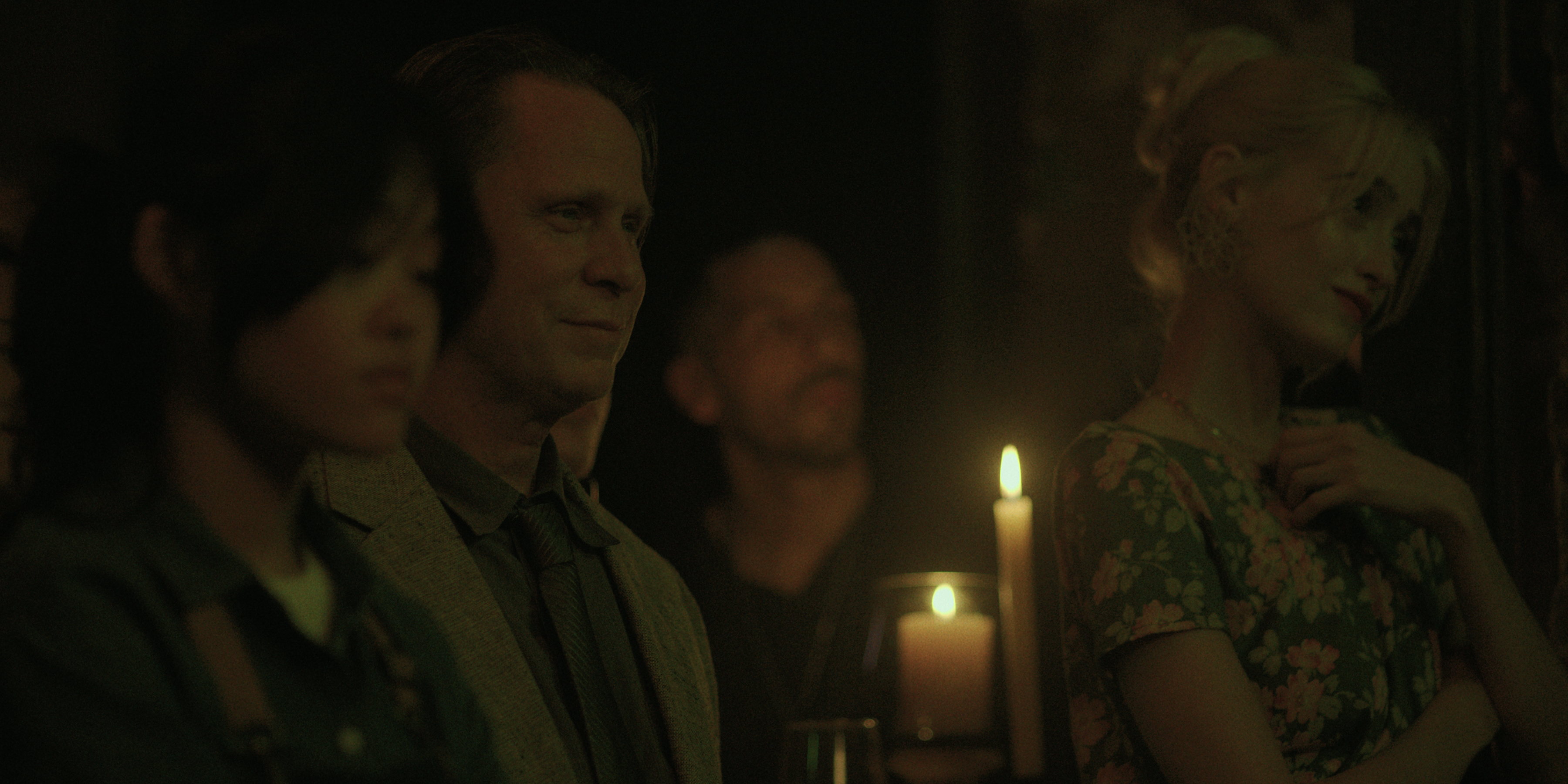 a group of people including gus birney as mel watch a performance in a dimly lit room in black rabbit