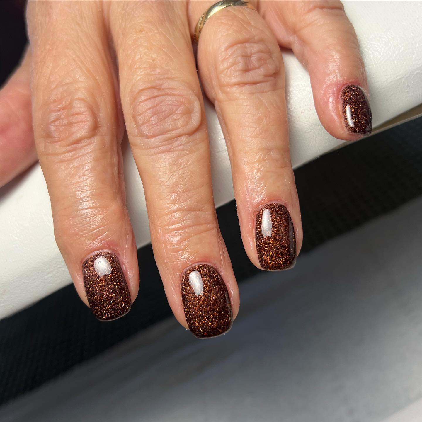 Sparkly Coffee manicure close up on one hand with a silver ring