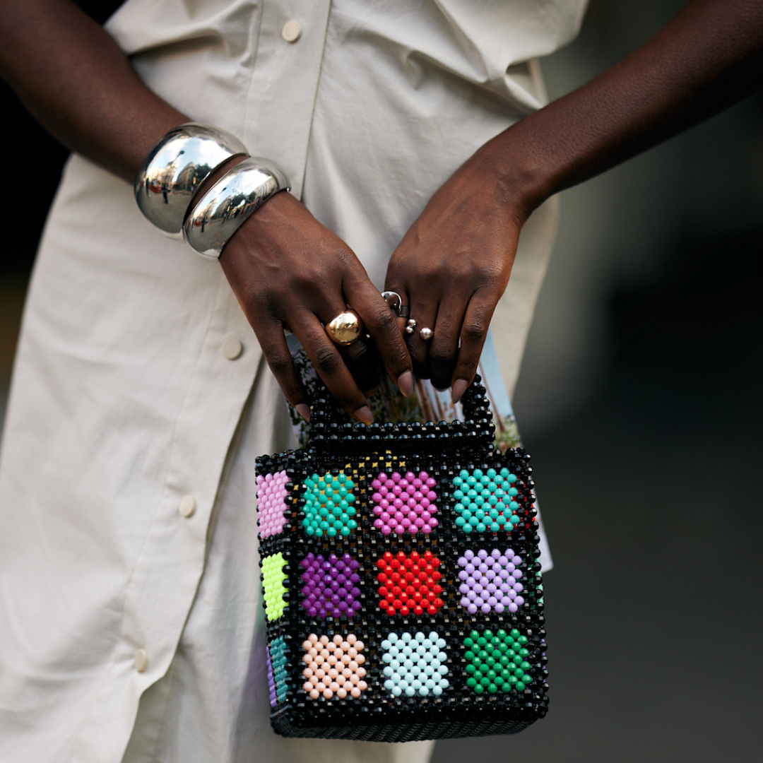 woman wearing silver bangles carrying multicolored beaded bag 