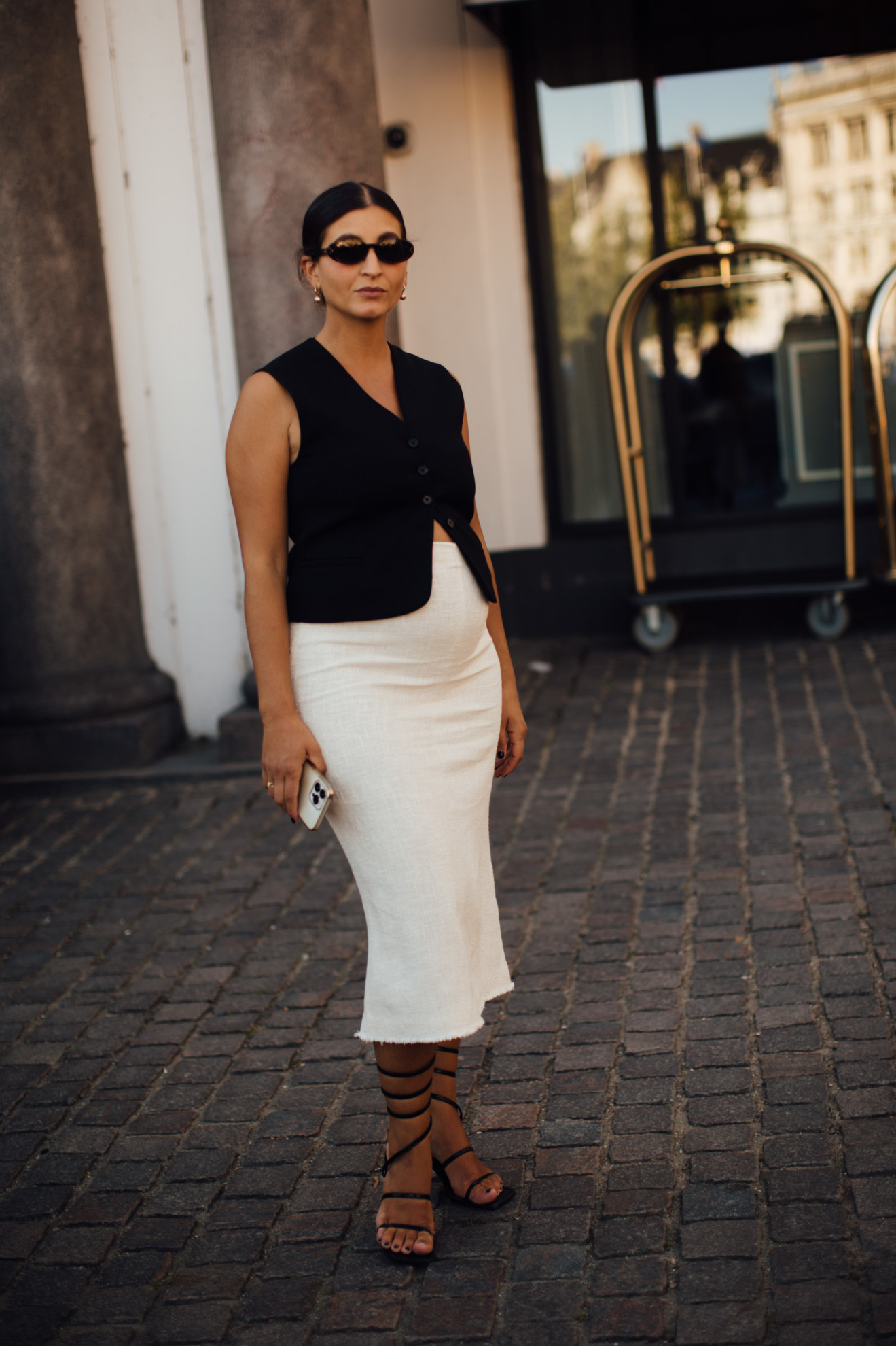woman wearing black vest, white skirt, and black sandals